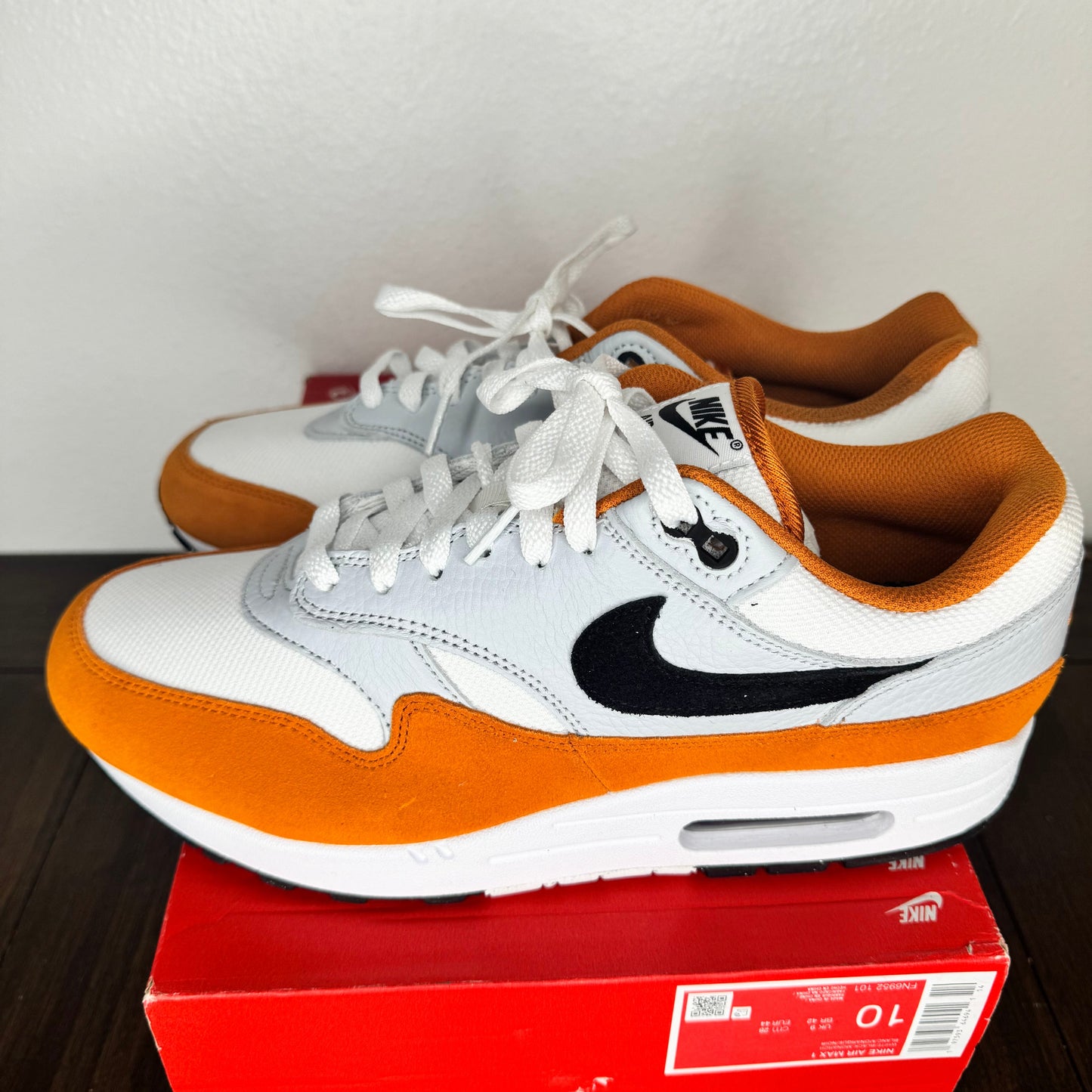 Orange and white sneakers on a red box with a white background