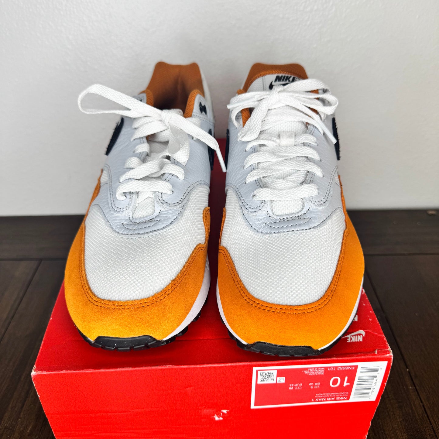 White and orange sneakers on a red box with a white background